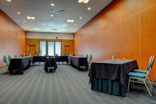 a conference room with long tables and blue chairs at VIP Executive Santa Iria Hotel in Santa Iria da Azóia