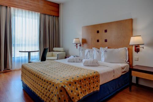 Cette chambre comprend un grand lit et une grande fenêtre. dans l'établissement VIP Executive Santa Iria Hotel, à Santa Iria da Azóia