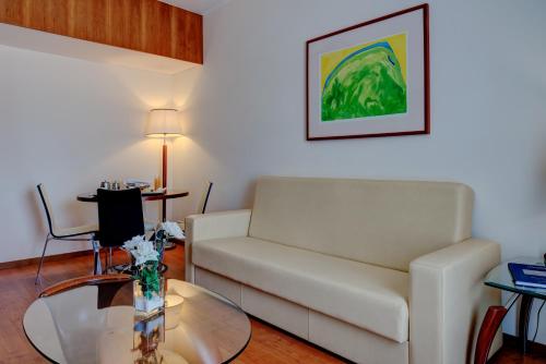 a living room with a white couch and a glass table at VIP Executive Santa Iria Hotel in Santa Iria da Azóia