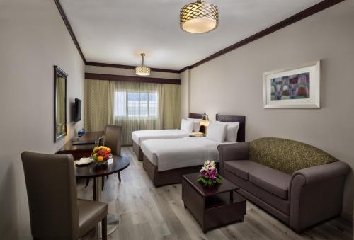 Savoy Crest Hotel Apartment - Bur Dubai في دبي: غرفه فندقيه بسرير واريكه