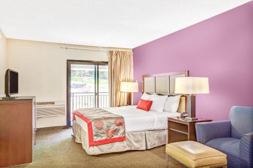 a hotel room with a bed and a tv and a chair at Ramada by Wyndham Rockaway in Rockaway