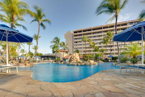 een zwembad van het resort met palmbomen en blauwe parasols bij Barceló Aruba - All Inclusive in Palm-Eagle Beach