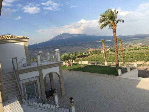 a house with a palm tree and a view of a mountain at Borgo Ginuga in Centuripe