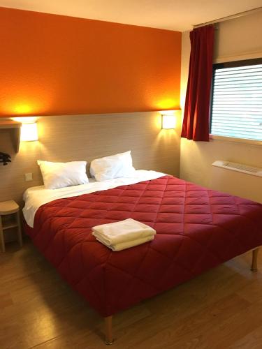 a bedroom with a large bed with a red blanket at Premiere Classe Paris Ouest - Nanterre - La Defense in Nanterre
