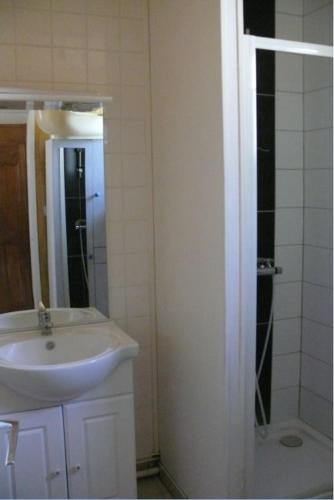 a white bathroom with a sink and a shower at Maison Bord Du Lac in Marcillac-la-Croisille