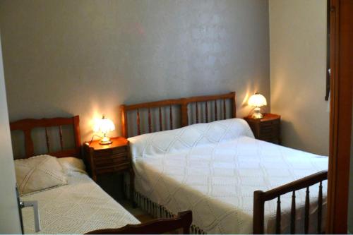 a bedroom with two beds and two lamps on tables at Maison Bord Du Lac in Marcillac-la-Croisille