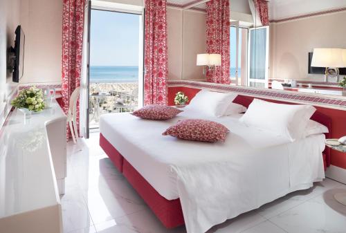 a bedroom with a large bed and a large window at Hotel Milton Rimini in Rimini