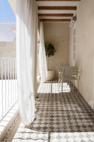 a balcony with white curtains and a table and a plant at Jardí de Ses Bruixes Boutique Hotel in Mahón