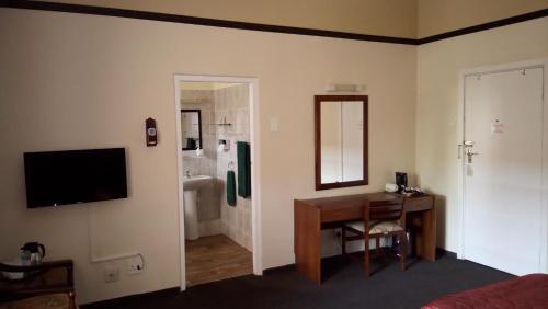 a bedroom with a desk and a bathroom with a sink at Royal Hotel Ladysmith in Ladysmith