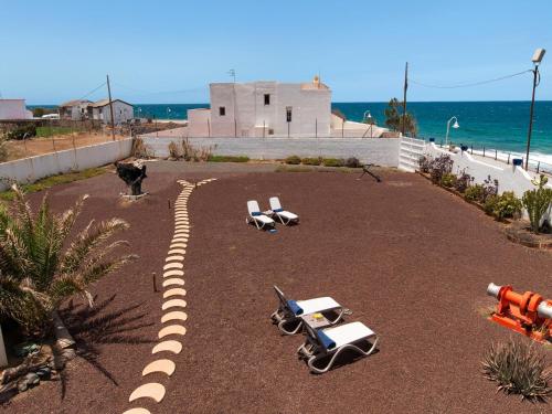a group of beach chairs on the ground near the ocean at Agaete Beach Rental at Volcanic Natural Pools by VillaGranCanaria in Agaete