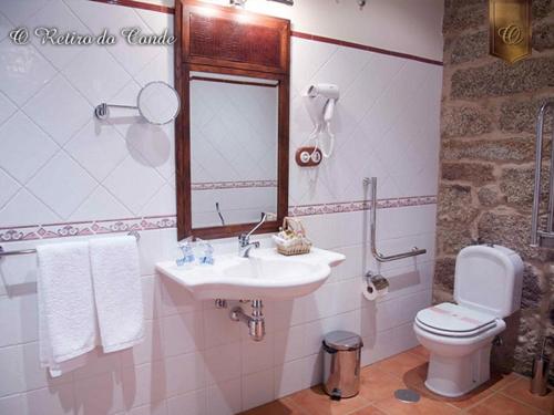 a bathroom with a sink and a toilet and a mirror at O Retiro do Conde in Villaza