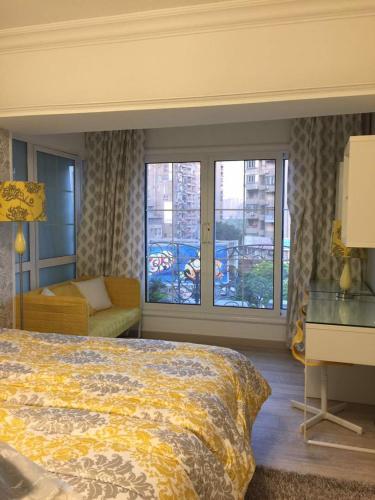 a bedroom with a bed and a couch and windows at Luxury Mohandeseen Apartment in Cairo