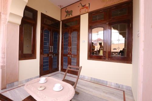 una mesa y una silla en una habitación con ventanas en Harsidhi Haveli en Bikaner