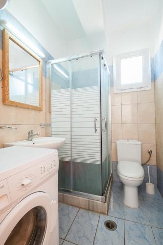 a bathroom with a toilet and a sink and a washing machine at Ypsipyli in Myrina