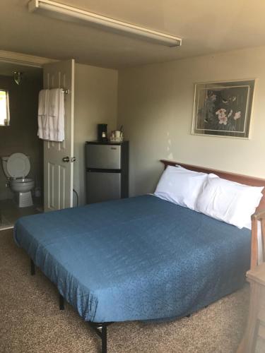 a bedroom with a bed with a blue blanket at Hillside Motel in Lake George
