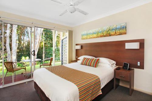 1 dormitorio con 1 cama grande y balcón en Flynns on Surf Beach Villas, en Port Macquarie