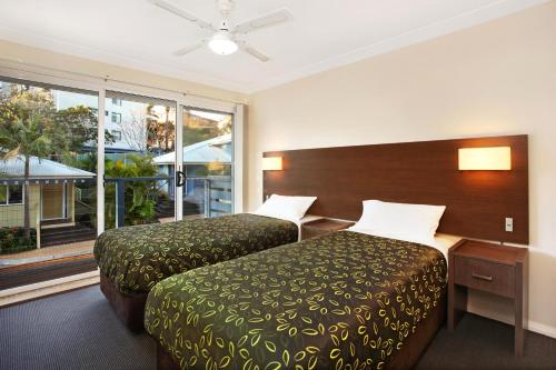 a hotel room with two beds and a large window at Flynns on Surf Beach Villas in Port Macquarie