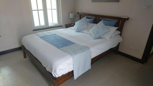 a bedroom with a large bed with white sheets and blue pillows at Balinese villa with private pool in Hua Hin