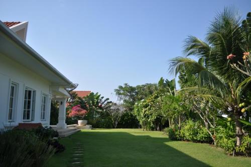 a yard of a house with green grass and palm trees at Balinese villa with private pool in Hua Hin