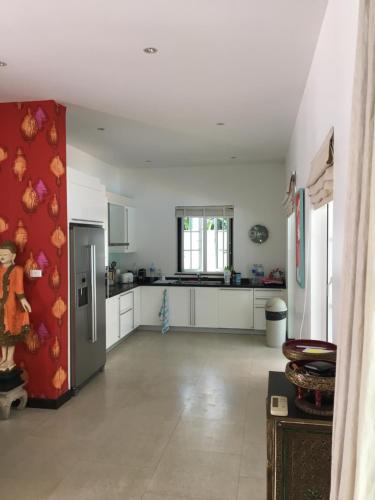 a large kitchen with white cabinets and a refrigerator at Balinese villa with private pool in Hua Hin