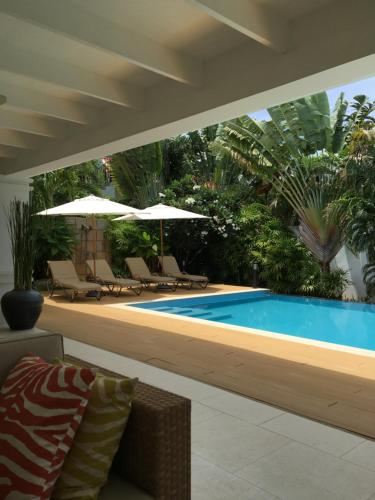 a pool with chairs and umbrellas in a backyard at Balinese villa with private pool in Hua Hin