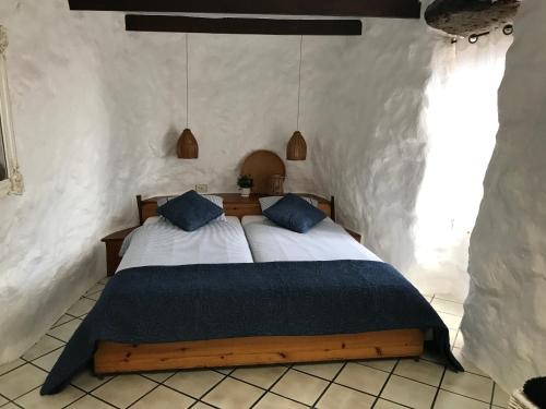 a bedroom with a large bed with blue pillows at Finca Antigua in Las Breñas