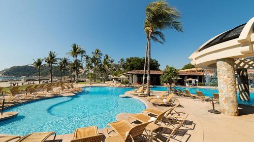a resort swimming pool with chairs and palm trees at Pierre Mundo Imperial Riviera Diamante Acapulco in Acapulco