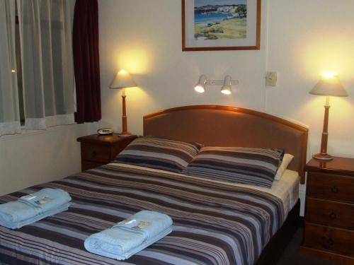 a bedroom with a bed with two towels on it at Aquarius Motel in Belmont