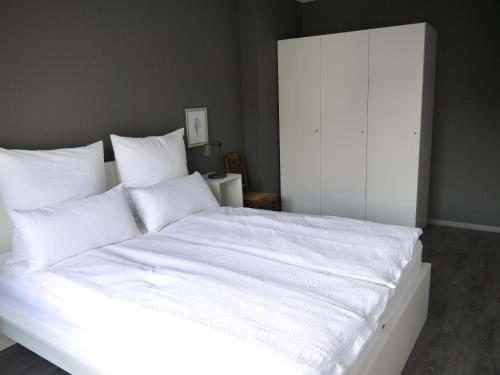 ein großes weißes Bett mit weißer Bettwäsche und Kissen in der Unterkunft Lebendiges Linden in Hannover
