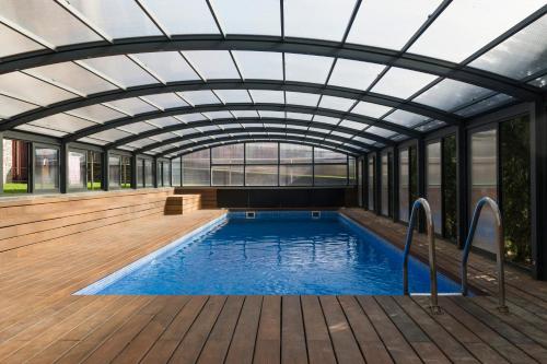 an indoor swimming pool with a glass ceiling and a wooden deck at Apartaments Turístics Puigcerdà - La Closa in Puigcerdà