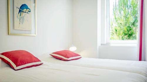 a bed with two red pillows and a window at Magoito1 in Sintra