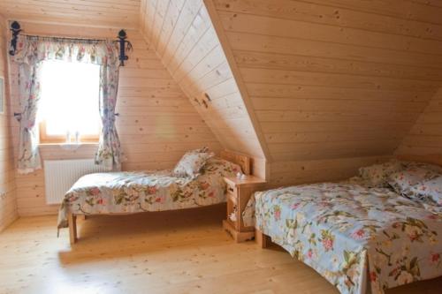 コシチェリスコにあるSmerkowy Dworekのベッド2台と窓が備わる屋根裏部屋です。
