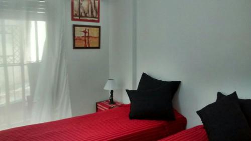 a bedroom with a red bed with black pillows at Apartamento Recoleta in Buenos Aires