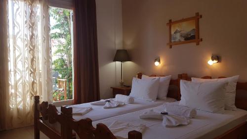 a bedroom with two beds with white sheets and a window at Aiolos House in Skiathos Town