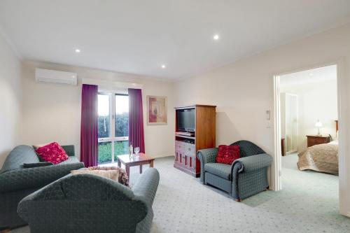 a living room with two chairs and a television at Best Western Crystal Inn in Bendigo