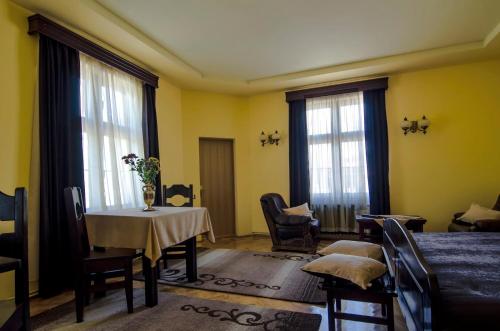 a room with a table and chairs and windows at Iris Villa in Vatra Dornei