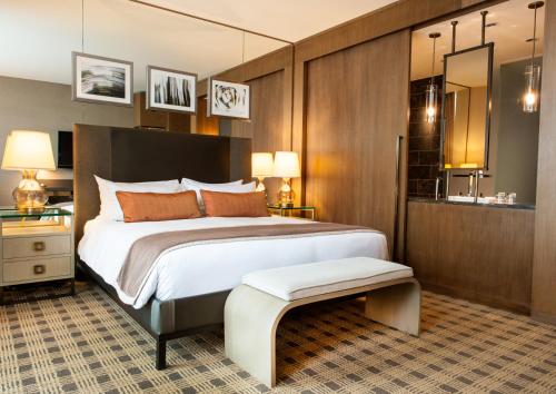 a bedroom with a large white bed and a mirror at Loden Vancouver in Vancouver