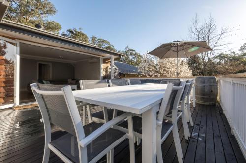 a white table and chairs on a deck with an umbrella at QUPI HOUSE formerly Rex's Yarra Valley House in Healesville