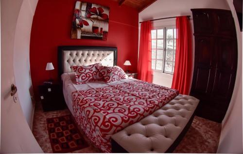 Dormitorio rojo con cama y ventana en El Zuriaco en Santa Rosa de Calamuchita