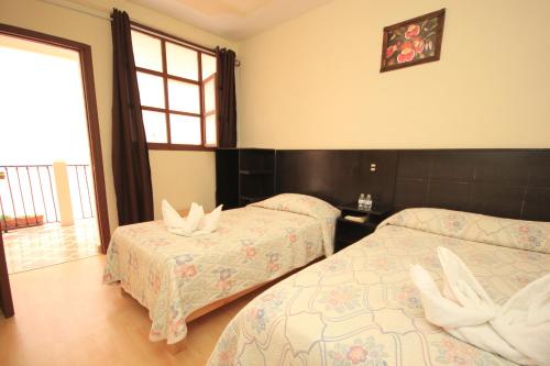 a hotel room with two beds and a window at Hotel San Martin in San Cristóbal de Las Casas