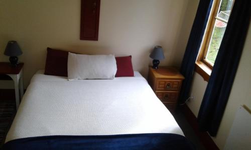 a bedroom with a white bed with two pillows and a window at Greenstone Retreat in Kumara