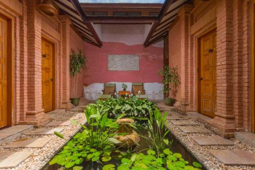 a patio with a pond with plants and chairs at The Hotel @ Tharabar Gate in Bagan