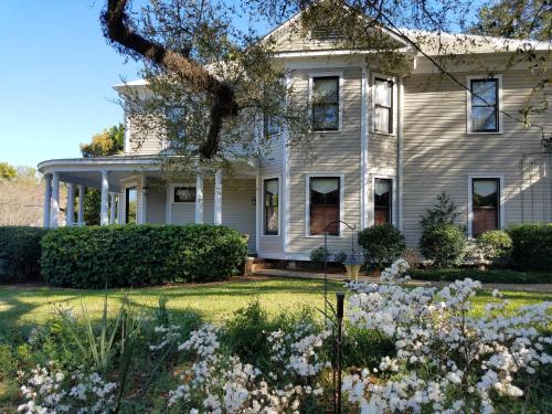 托馬斯維爾的住宿－Thomasville Bed and Breakfast，院子里的白色房子,鲜花盛开