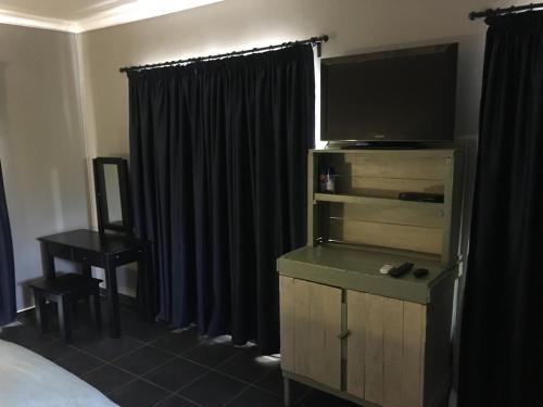 a bedroom with a bed and a dresser with a television at Bottom of Boden in Benoni