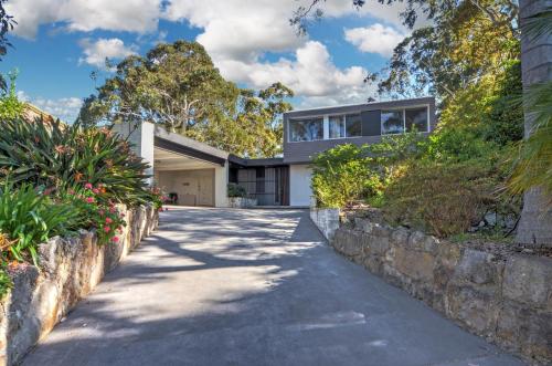 a home with a stone retaining wall and a driveway at Treehouse Jervis Bay in Vincentia