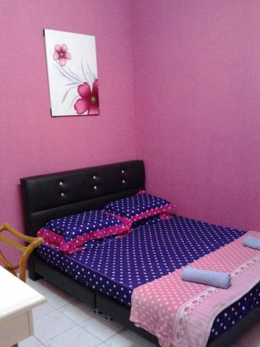 a bedroom with a bed and a pink wall at Adiana Homestay in Kuah