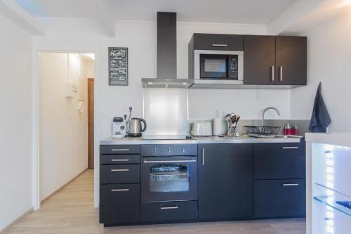 una cucina blu con piano cottura e forno a microonde di SweetHome Dijon - Black & White a Digione