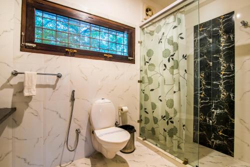 a bathroom with a toilet and a glass shower at The Coral Tree Boutique Homestay in Agra