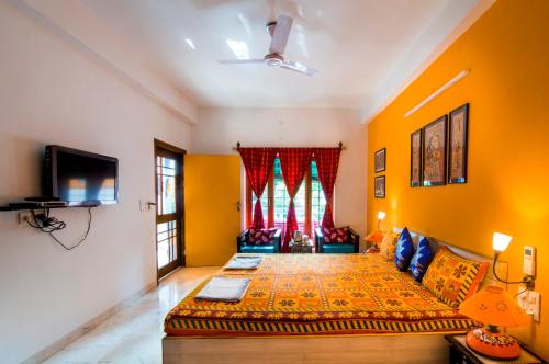 a room with a bed and a couch and a tv at The Coral Tree Boutique Homestay in Agra