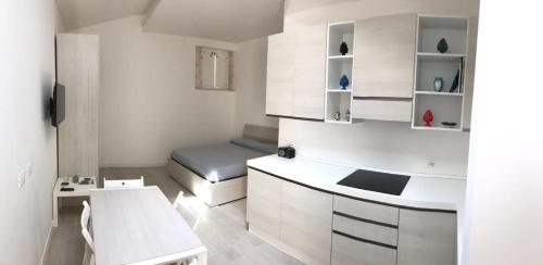 シラクーサにあるLa casetta di Ortigiaのベッドとキッチン付きの小さな白い部屋